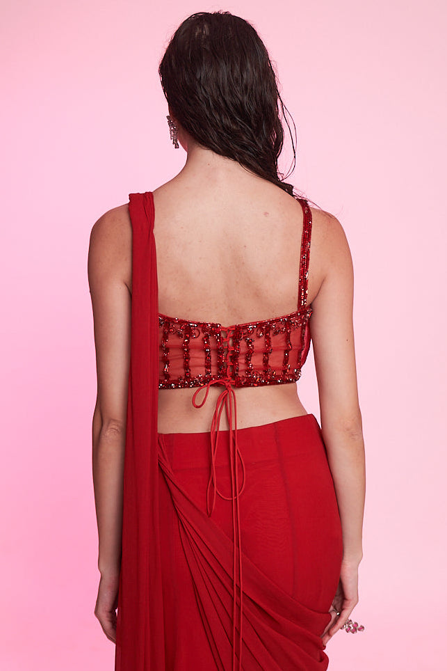 Scarlet red draped saree with an intricately embellished corset blouse