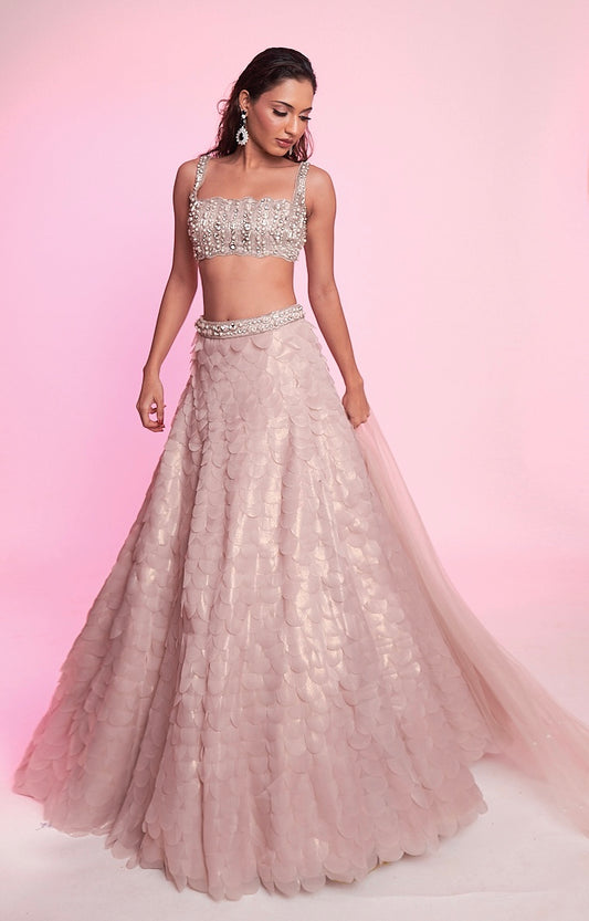 Blush pink lehenga with pearl-embellished blouse and layered petal-textured skirt.